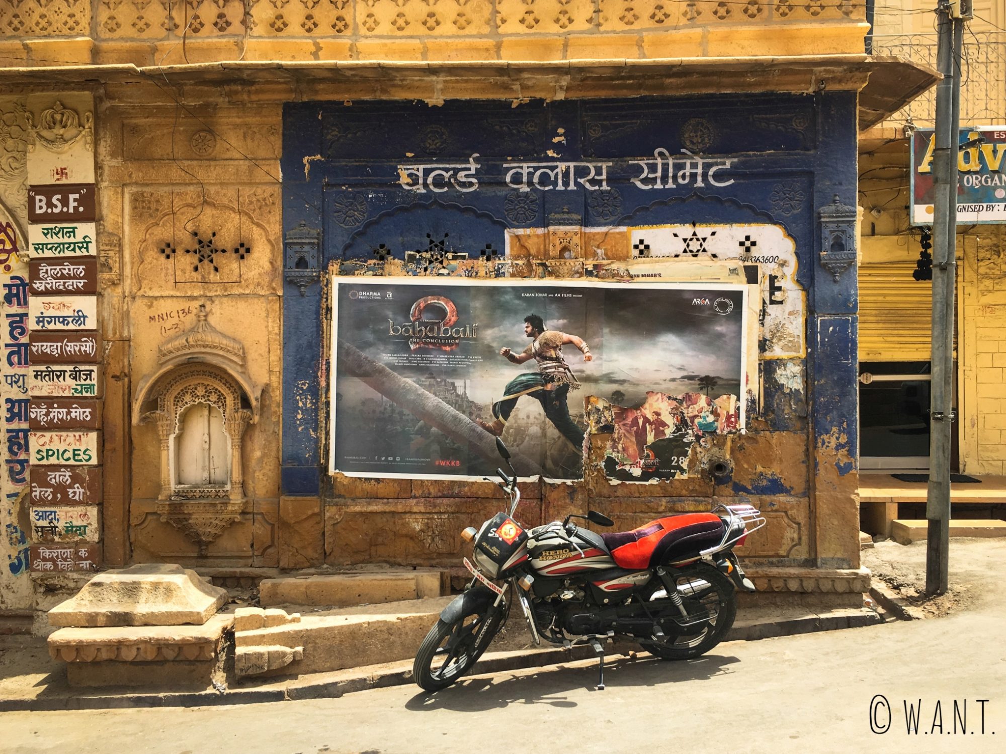 Moto garée devant une affiche de film indien dans les rues de Jaisalmer