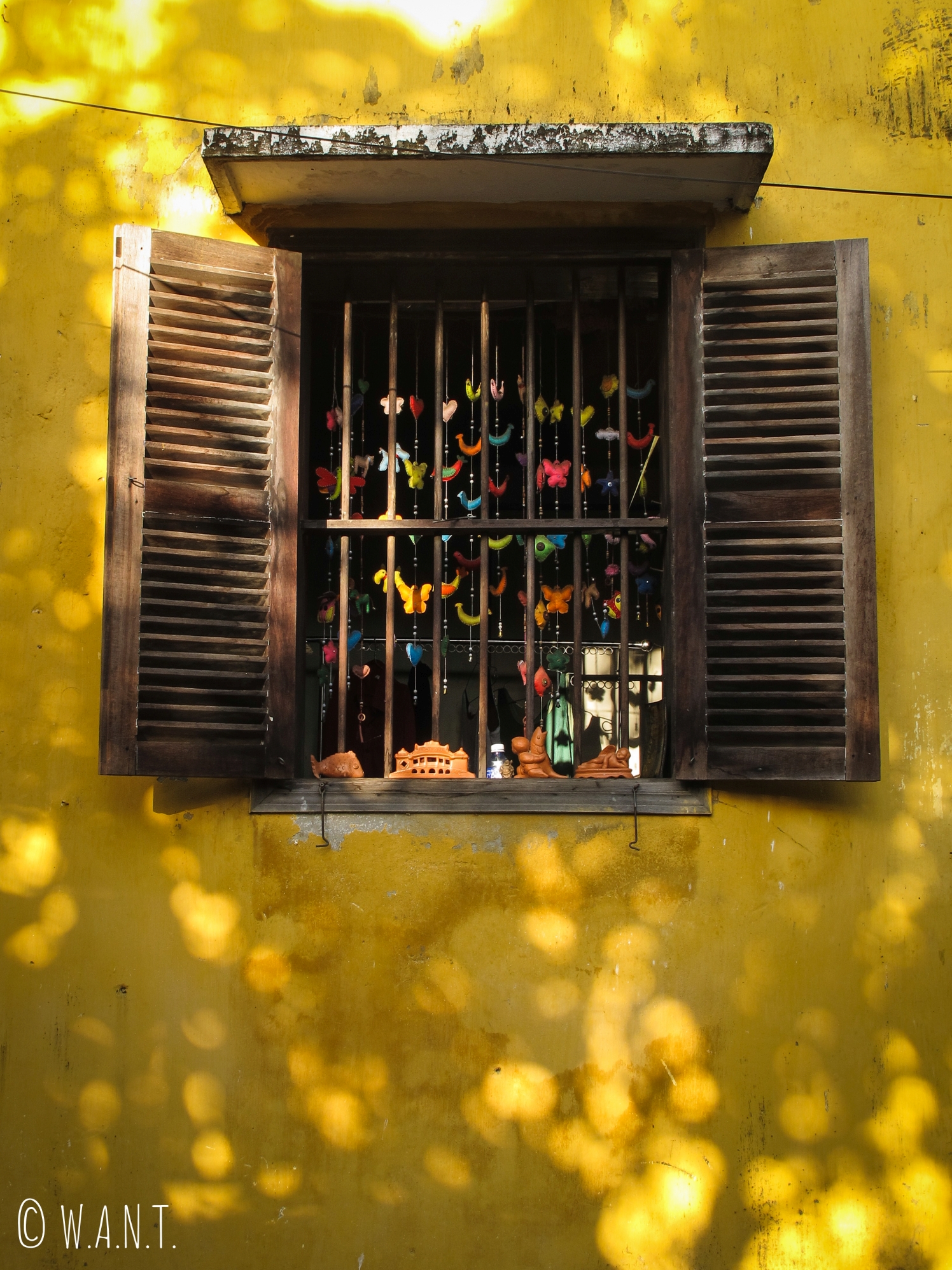 Fenêtre d'une bâtisse jaune de la vieille ville de Hoi An