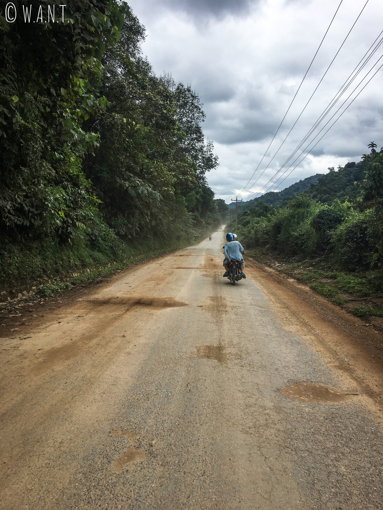 Agnès et Jilles de dos, sur une portion de route entre Luang Namtha et Muang Sing